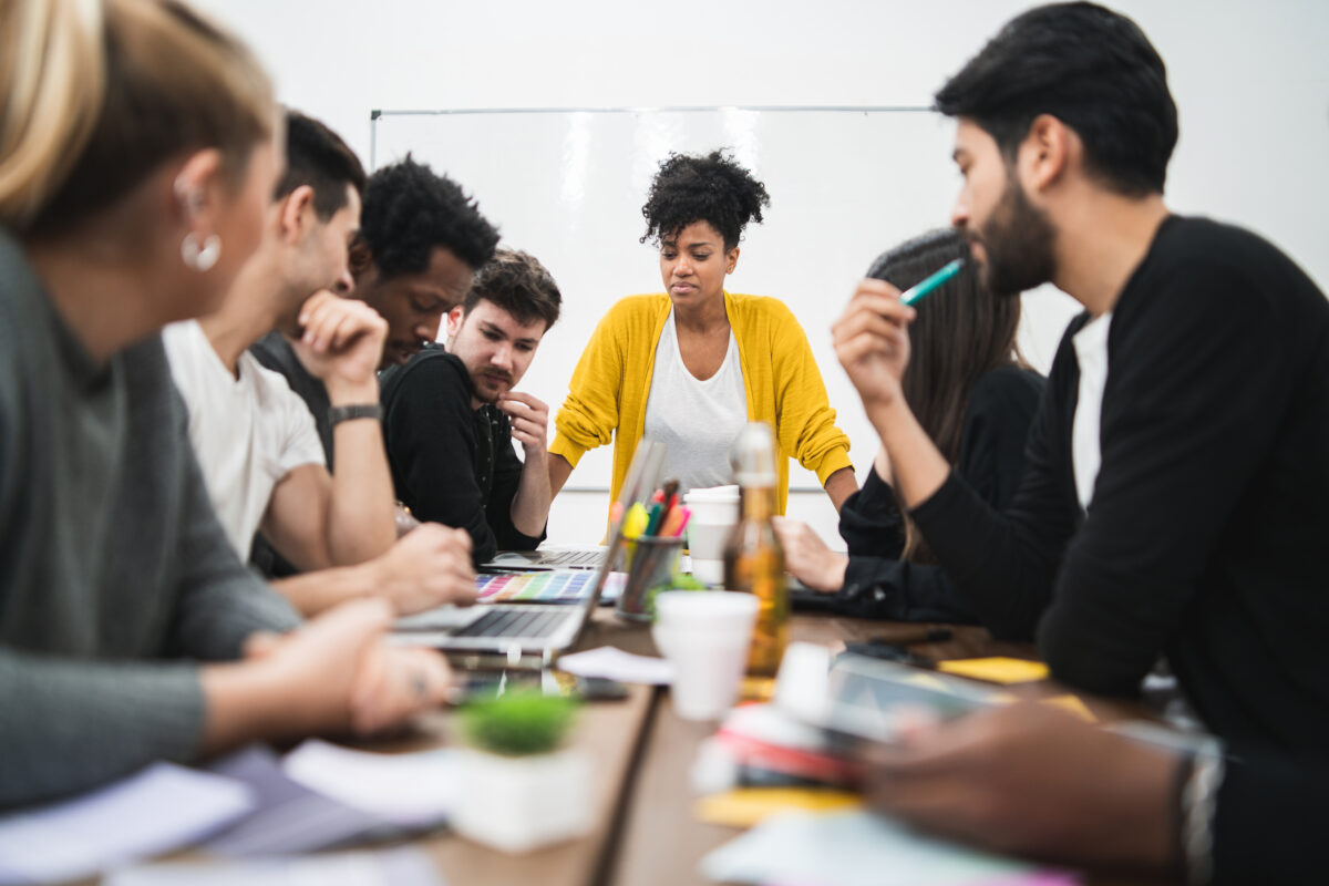 Manager woman leading a brainstorming meeting with a group of creative designers in the office. Leader and business concept.