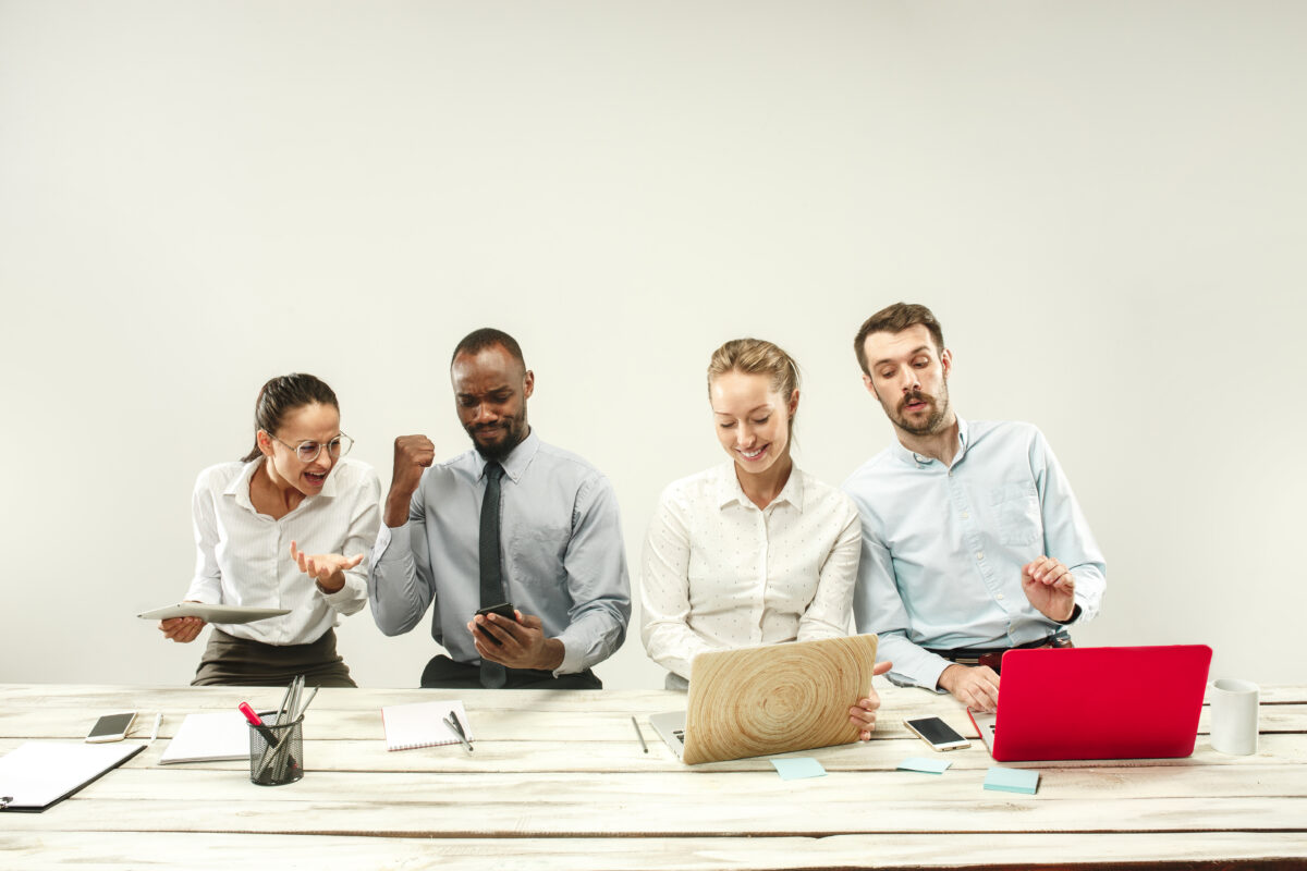 Young african and caucasian men and women sitting at office and working on laptops. The business, emotions, team, teamwork, workplace, leadership, meeting concept. different emotions of colleagues